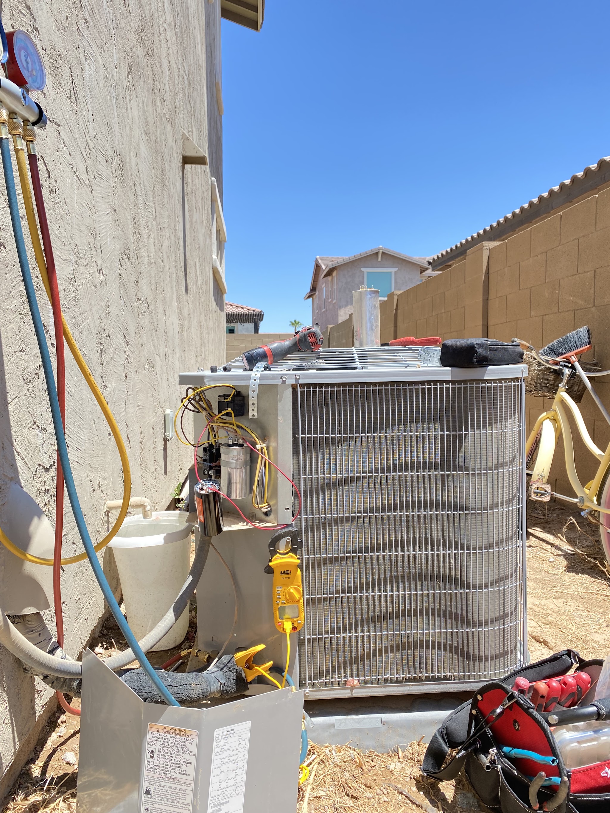 A residential condenser opened up for diagnostics with a clamp meter on the wiring