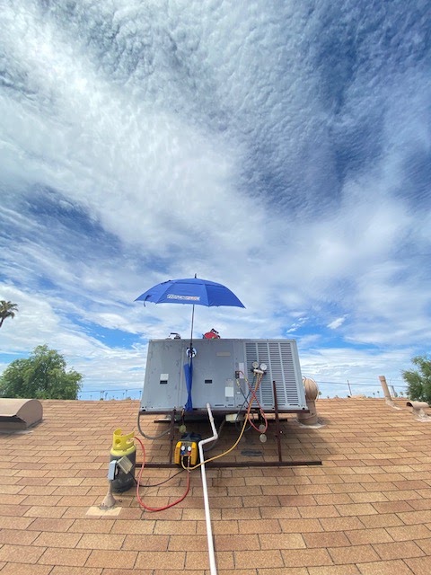 A rooftop unit being serviced under a shade umbrella on a Phoenix roof